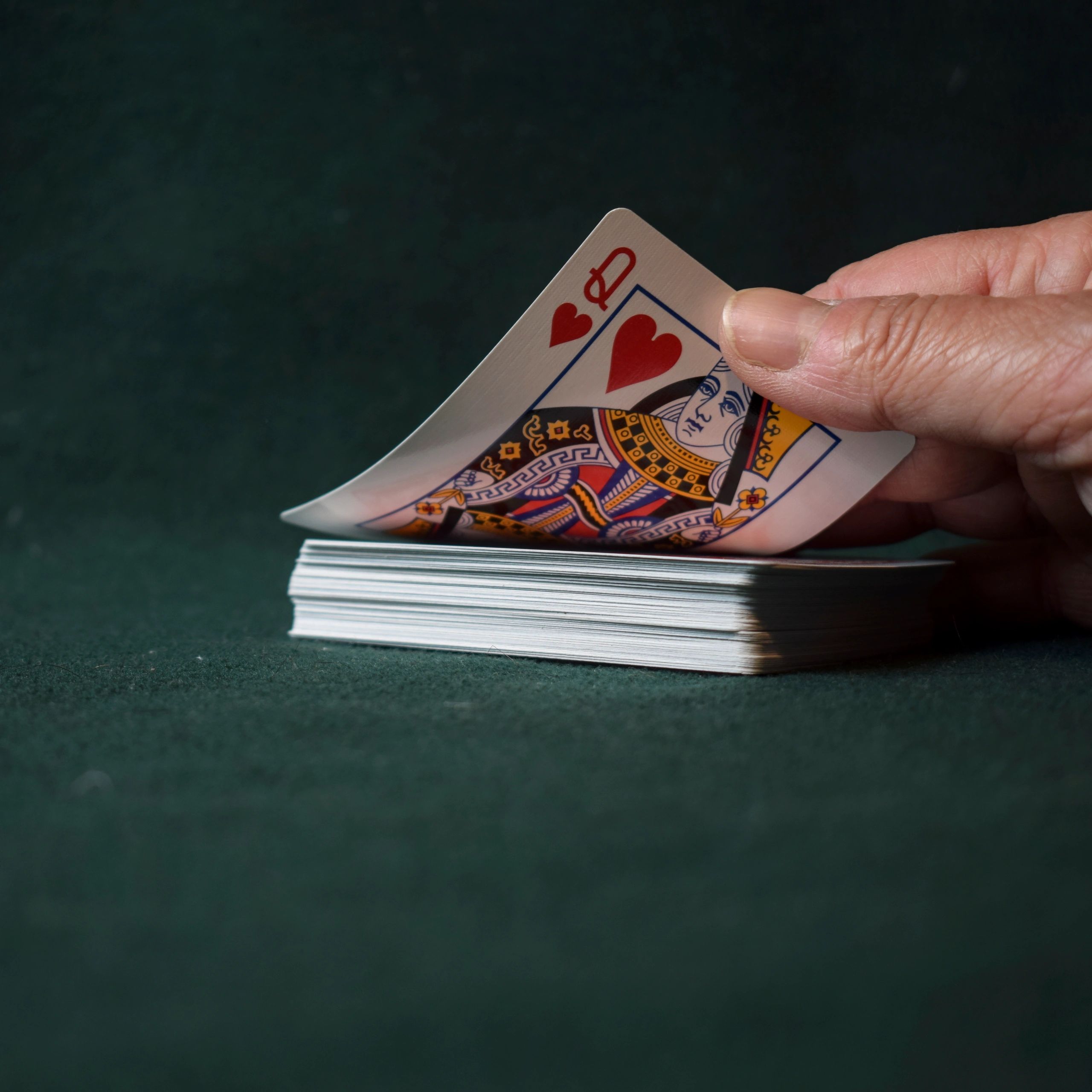Hand revealing a playing card on a green table